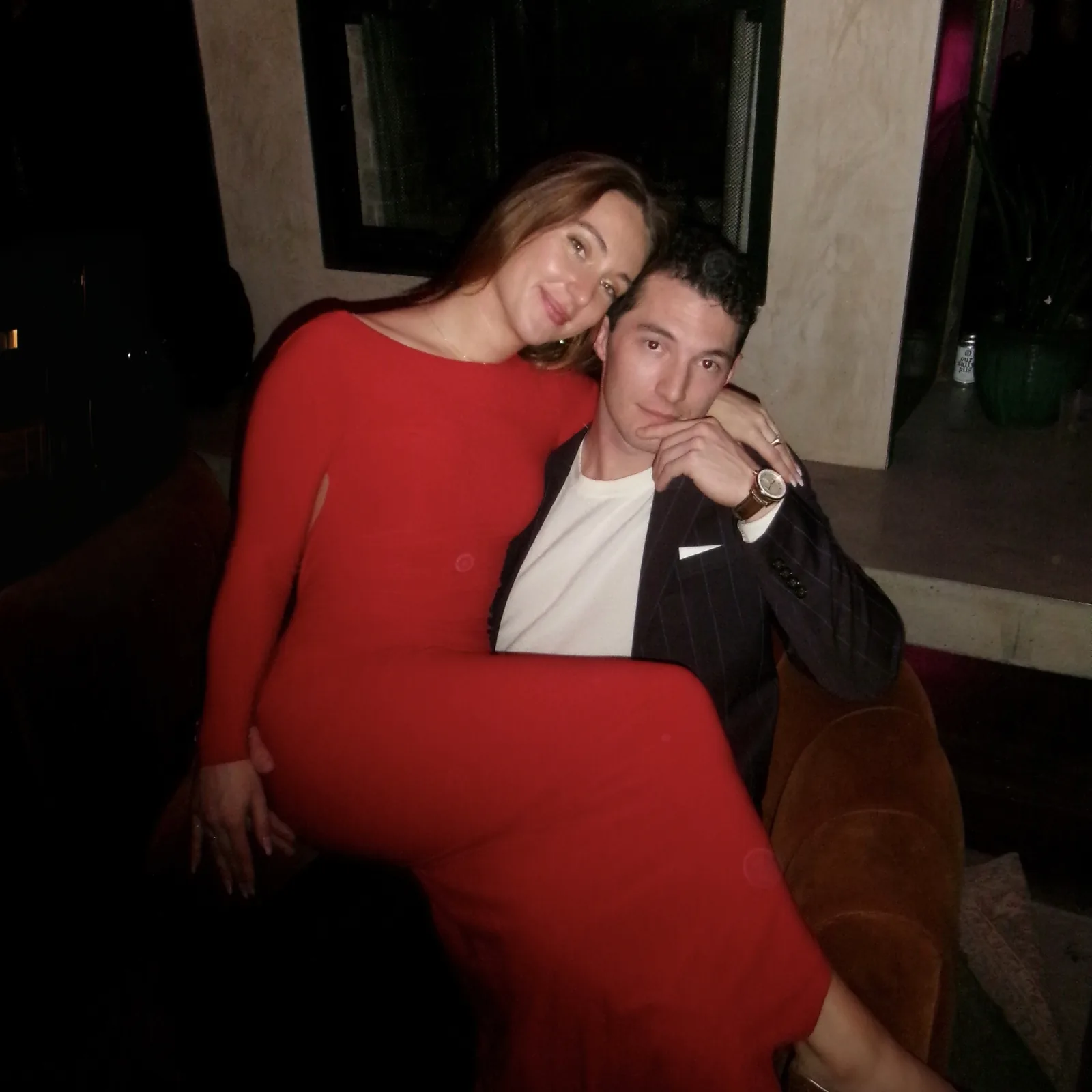 Meaghan and Roman on a couch, Meaghan in a red dress
