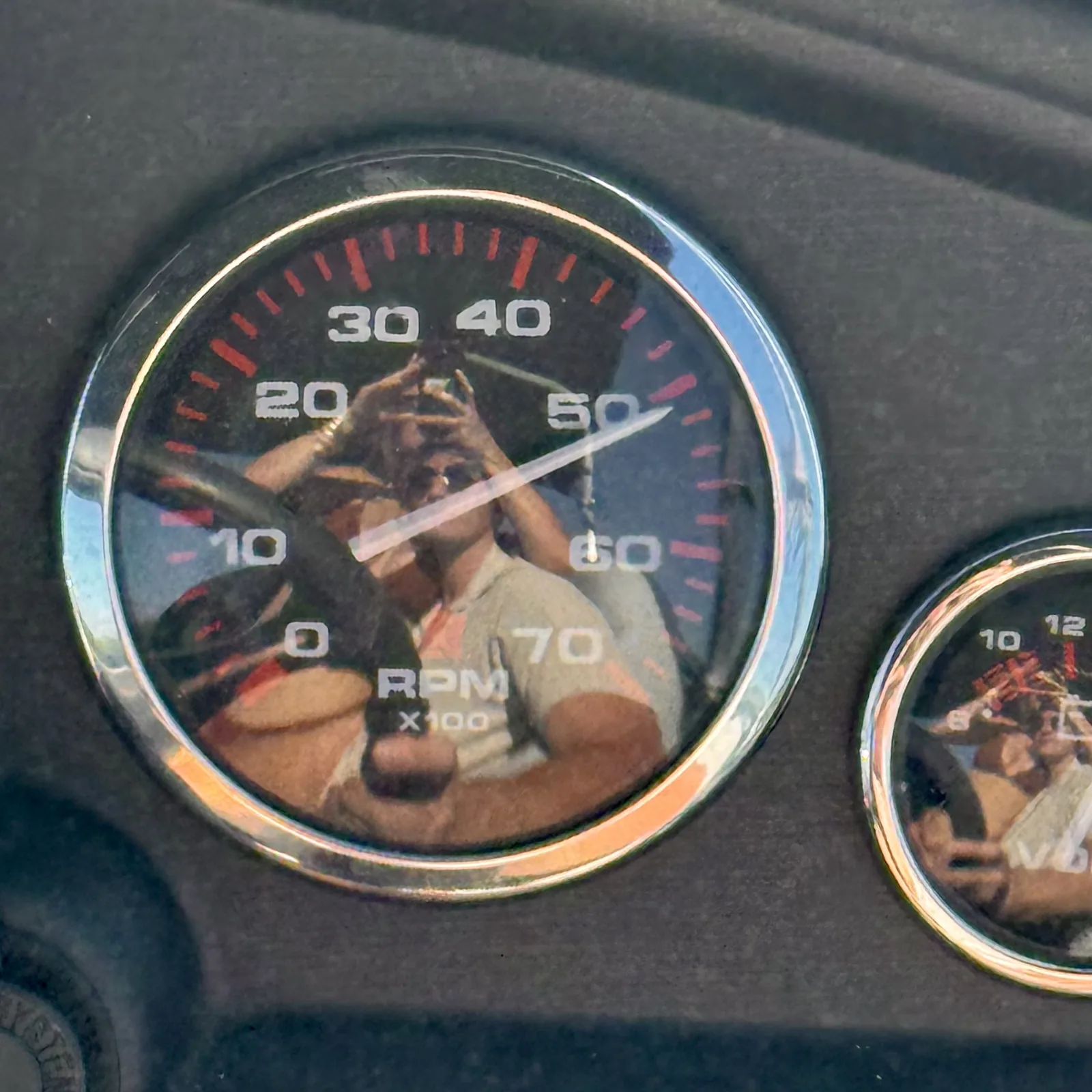 Meaghan and Roman reflected in a car's dashboard gauge